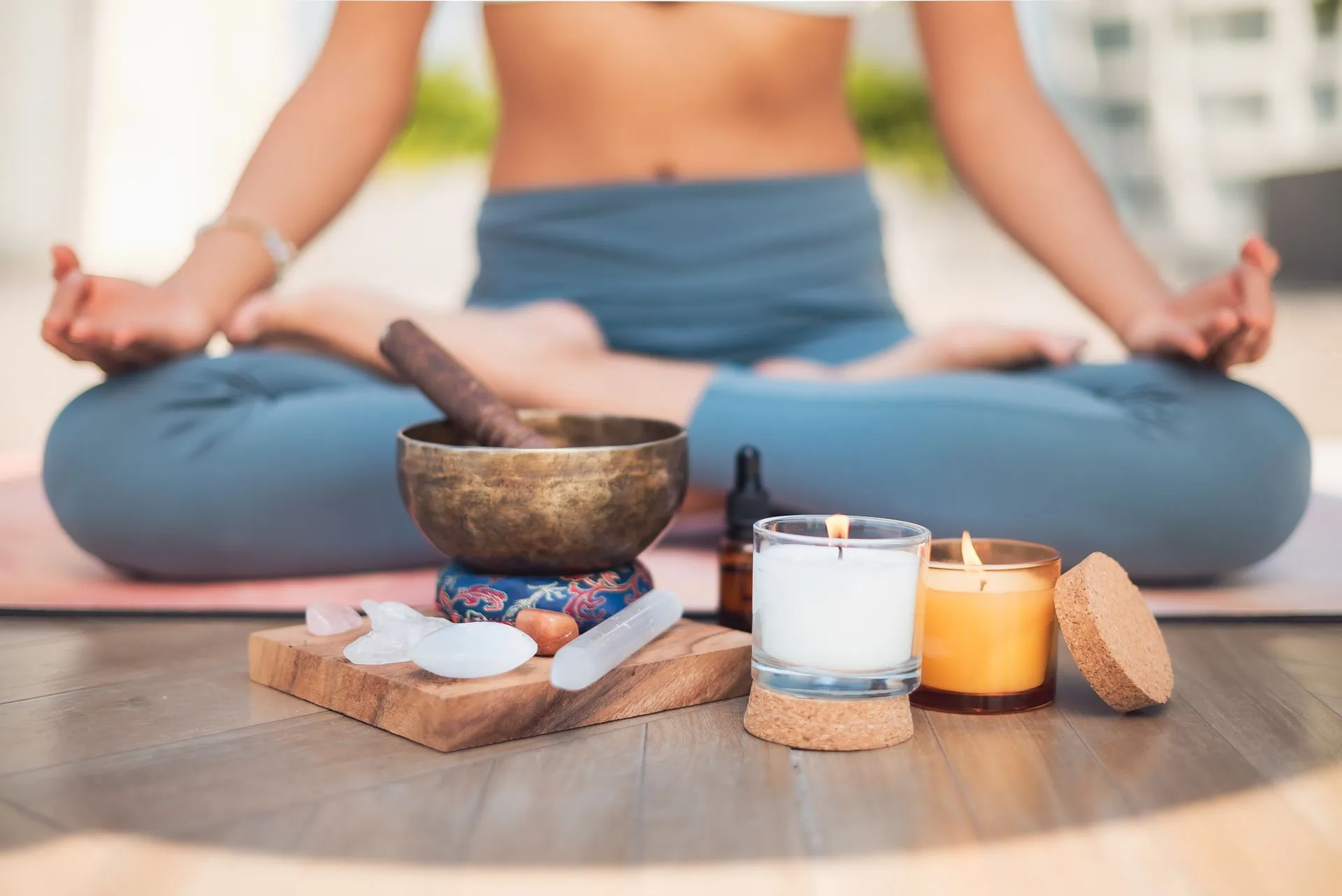 A person seated in meditation with a singing bowl and candles in front of them